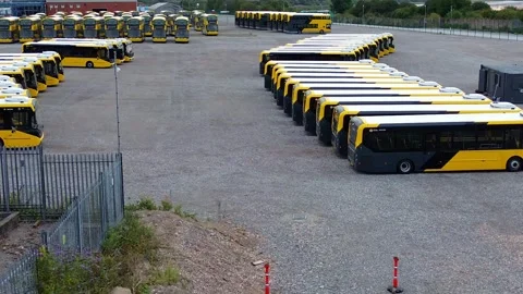 Rows of electric busses aerial view parked on industrial site low dolly left 库存影片 342404046