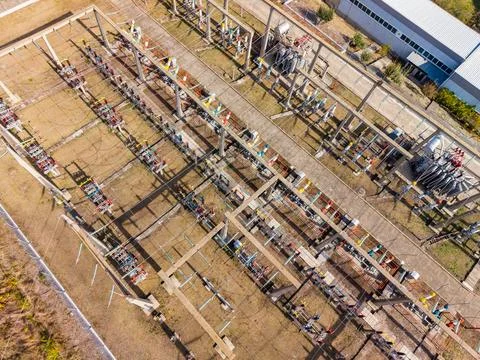 Rows of electrical equipment, steel frames, and power lines fill an outdoor s 库存照片