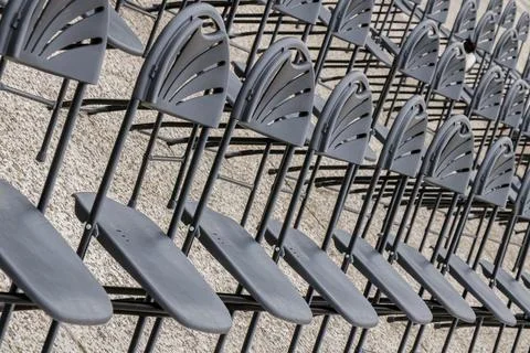 Rows of empty black chairs arranged in neat order at an outdoor venue befor.. Stock Photos
