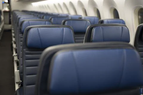 Rows of empty blue leather seats on a commercial airplane. Stock Photos