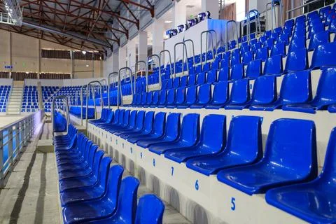 Rows of empty blue plastic seats in an indoor sports arena stadium Stock Photos