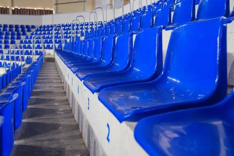 Rows of empty blue plastic seats in an indoor sports arena stadium Stock Photos