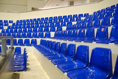 Rows of empty blue plastic seats in an indoor sports arena stadium Stock Photos