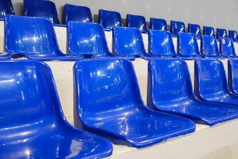 Rows of empty blue plastic seats in an indoor sports arena stadium Stock Photos