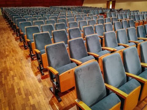 Rows of empty blue upholstered seats with wooden armrests in an auditorium Foto stock