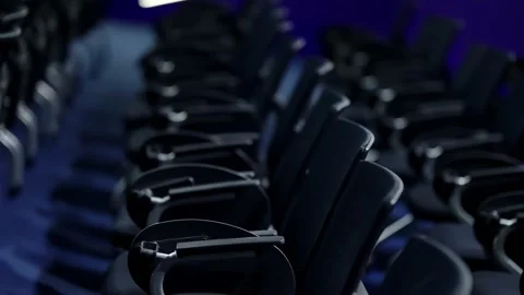 Rows of empty conference chairs with curved armrests in a dimly lit auditorium Video stock 325669375