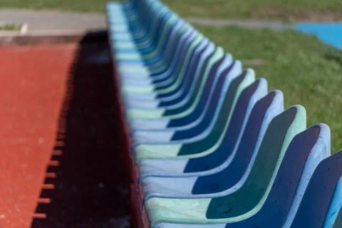 Rows of Empty Plastic Seats Lined up on a Sports Field During a Sunny Day W.. Stock Photos
