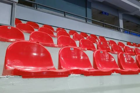 Rows of empty red plastic seats in a stadium tribune. Stock Photos