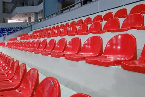Rows of empty red plastic seats in a stadium tribune. Stock Photos