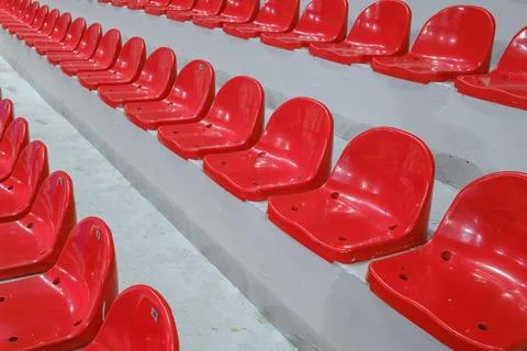 Rows of empty red plastic seats in a stadium tribune. Stock Photos