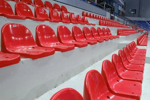 Rows of empty red plastic seats in a stadium tribune. Stock Photos