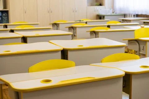 Rows of empty school desks with bright yellow accents inside a quiet primar.. Stock Photos