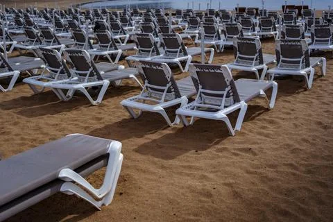Rows of empty sun loungers on sandy beach Stock Photos