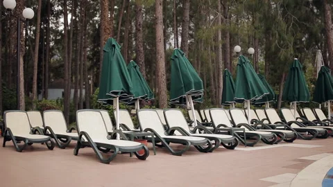 Rows of empty sun loungers stand in a wooded area at the pool. Stock Footage 100892152