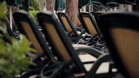 Rows of empty sun loungers stand in a wooded area at the pool. Stock Footage 100892226