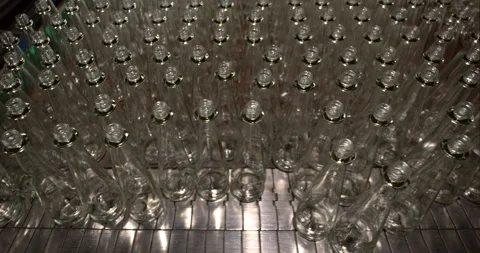 Rows of empty transparent glass bottles on a conveyor belt in a bottling plant Stock Footage 303107549