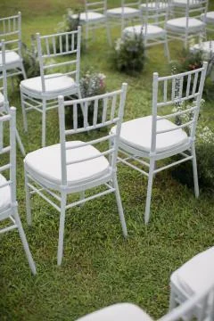 Rows of empty white folding chairs sitting on a lawn. Stock Photos