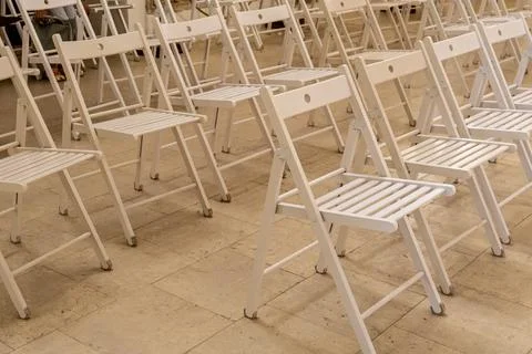 Rows of Empty White Folding Wooden Chairs for Outdoor Event Stock Photos
