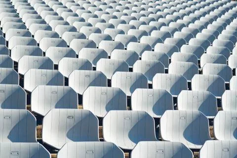 Rows of empty white plastic seats at the tribune in an open sports stadium Stock Photos