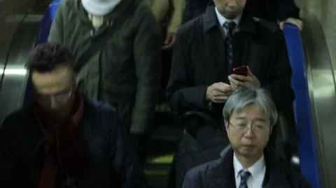 ROWS OF FACES DESCENDING ESCALATOR AT TRAIN STATION DURING RUSH HOURS IN TOKYO Stock-Footage 59922044