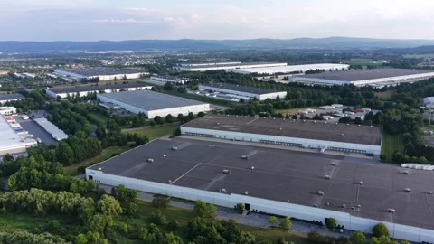 Rows of flat roofed warehouses fill industrial park bordered by trees in Stock Footage 340971075