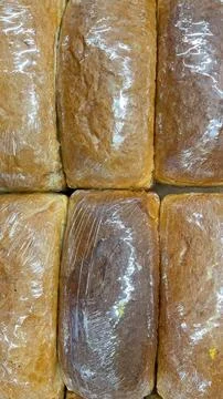 Rows of fresh, plastic-wrapped bread loaves ready for sale at a supermarket.. Foto stock