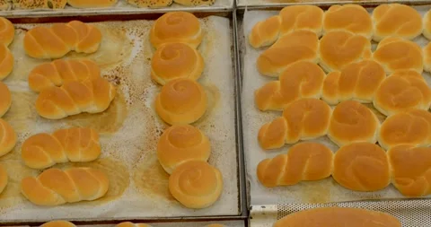 Rows of freshly baked rolls and buns on metal trays in bakery production, with Stock Footage 344583364