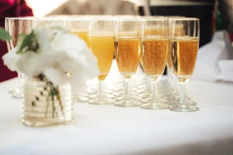 Rows of glasses with various drinks standing on white table cloth on festive Stock Photos