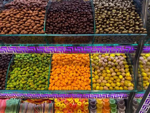 Rows of glossy chocolate style nuts displayed under decorative lighting in .. Stock Photos