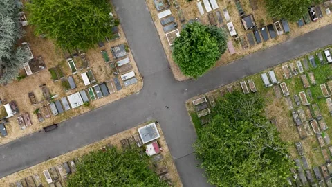 Rows of graves and headstones stretch across a cemetery where the grass between Stock Footage 343470822