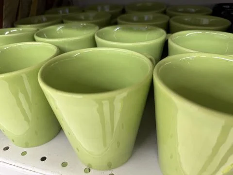 Rows of green ceramic cups displayed on a shelf, suitable for kitchen or ho.. Stock Photos