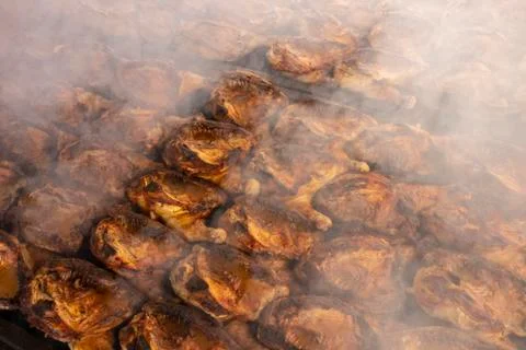 Rows of half chickens being roasted on a large barbecue grill Stock Photos