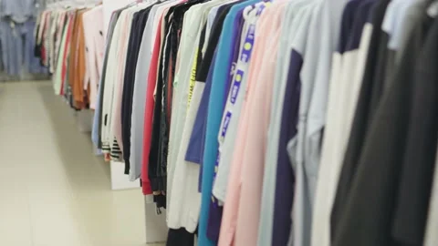 Rows of hanging clothes multicolor shirts hangers in shopping mall store Stock Footage 219757940