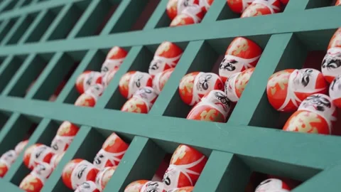 Rows of hundreds traditional Daruma dolls are arranged on green wooden shelves Stock Footage 344279310