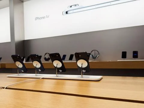 Rows of iPhone 17 display devices on wooden table in Apple store setting Stock Photos