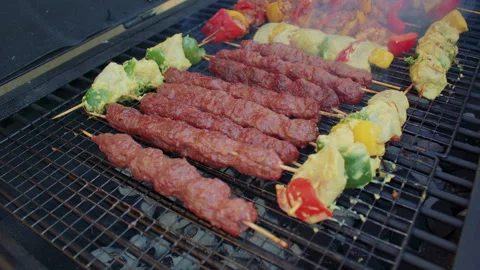 Rows of kebabs and grilled vegetables on a grilling grate of a barbeque brazier. Vídeos de archivo 309141112