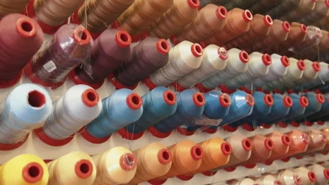 Rows of large spools of thread for sewing machines are sorted on a stand by Stock-Footage 151766411
