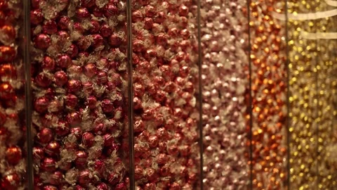 Rows of luxurious wrapped chocolates in shades of red, pink, orange, and gold fi Stock Footage 300115057