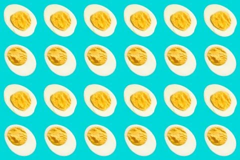 Rows of many halves of boiled eggs on a blue background Foto stock