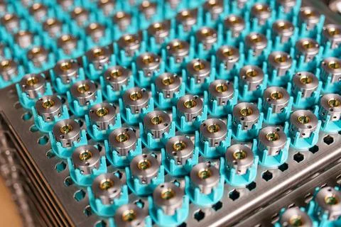 Rows of mechanical components arranged on trays in a factory setting during.. Stock Photos