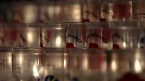 Rows of memorial candle flames burning in poppy glass holders. 4K locked tripod Stock Footage 142352465