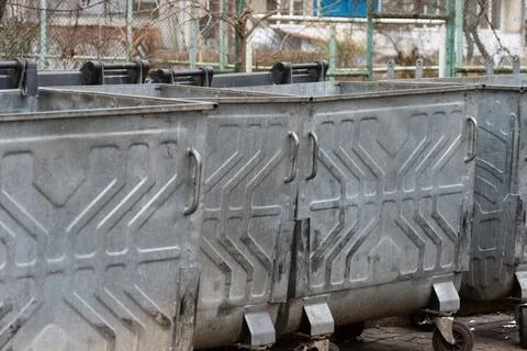 Rows of metal garbage containers filled with trash bags stand in an urban s.. Stock Photos