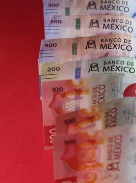 Rows of mexican banknotes of different denomination on the red background Stock Photos