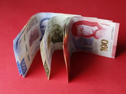 Rows of mexican banknotes of different denomination on the red background Stock Photos