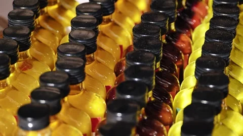 Rows of mini bottles with colorful liquid and black caps, displaying beverage Stock Footage 348215092
