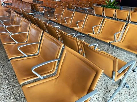 Rows of modern brown waiting chairs with metal frames arranged in a spacious Stock Photos
