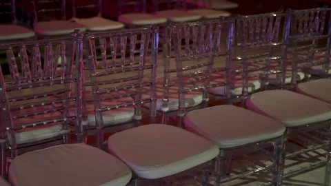Rows of modern, clear chairs with cushions under elegant purple pink event .. Stock Footage 322121590