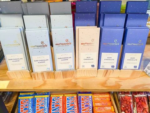 Rows of Moonstruck chocolate bars displayed on a wooden retail shelf. - Aug.. Fotos Stock