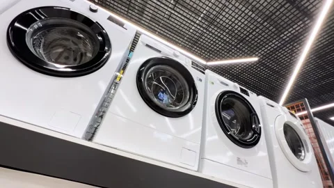 Rows of new washing machines stand in an appliance store. Low wide angle view Stock Footage 254631976