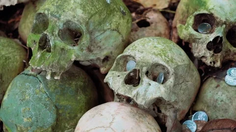 Rows of old mossy green human skulls with coins spread around - Trunyan Cemetery Video stock 65250354